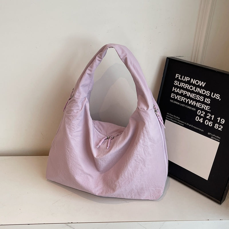 Pink handbag on a white surface with a framed quote in the background