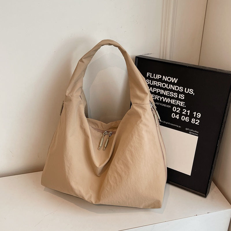 Beige handbag on a white surface with a black frame in the background