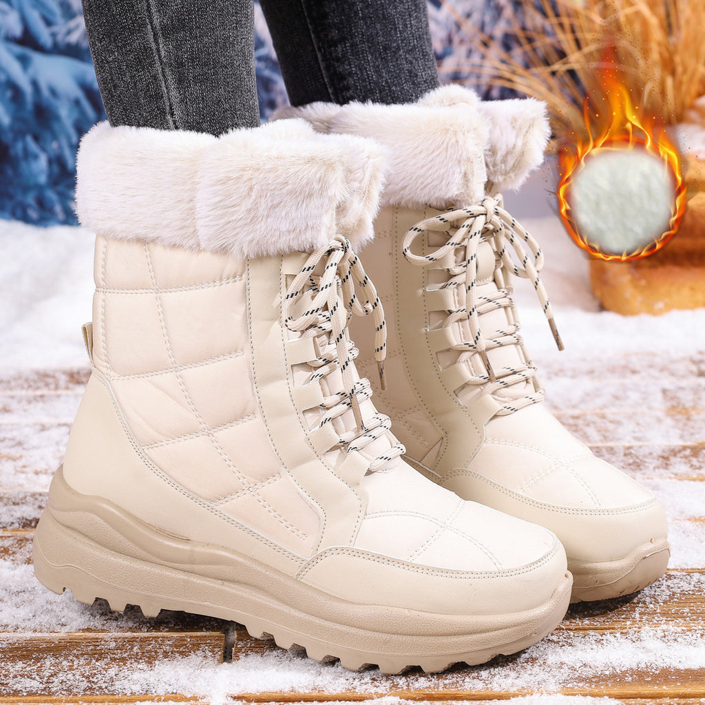 Beige winter boots with white fur lining worn by a person on a snowy ground.