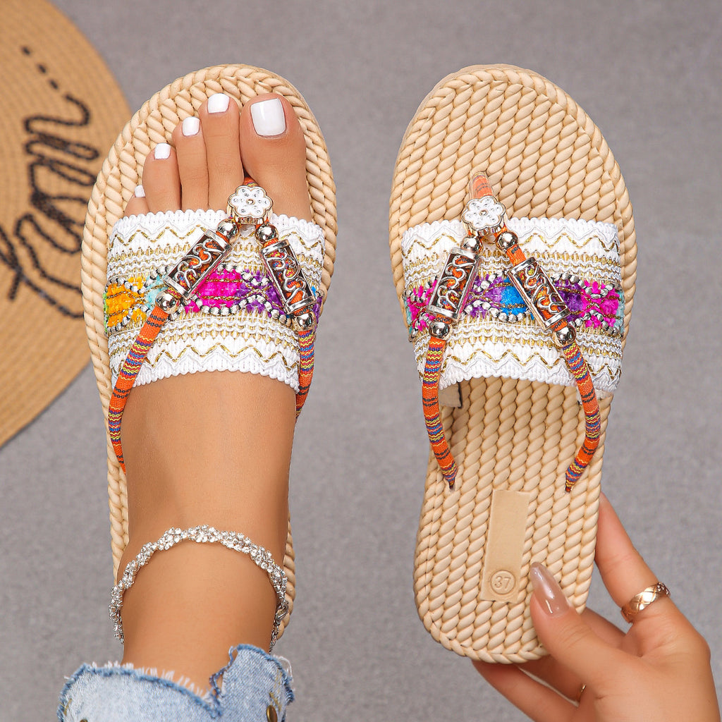 Beige sandals with colorful embellishments on a neutral background