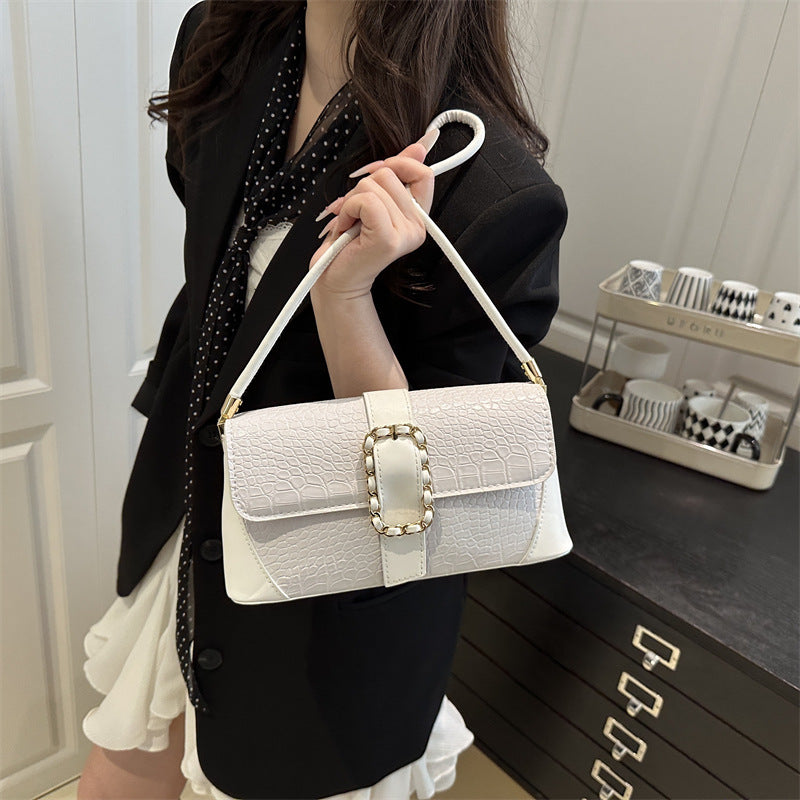 Woman holding a white handbag with decorative clasp in a room setting