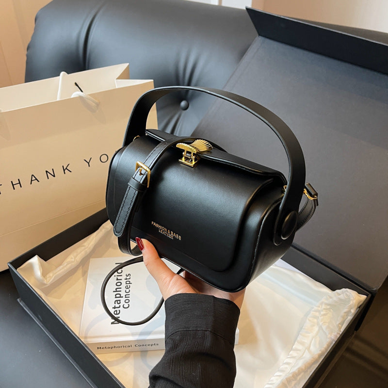 Black handbag held over a box with a 'thank you' bag and book inside.