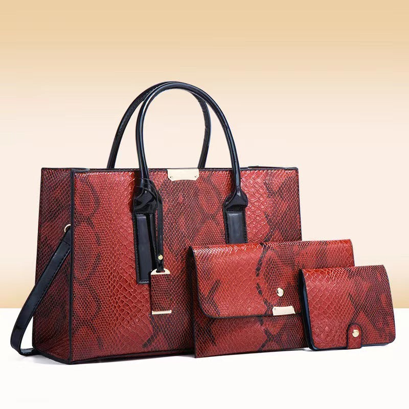 Red snakeskin pattern handbag set with matching wallet and pouch on a beige background