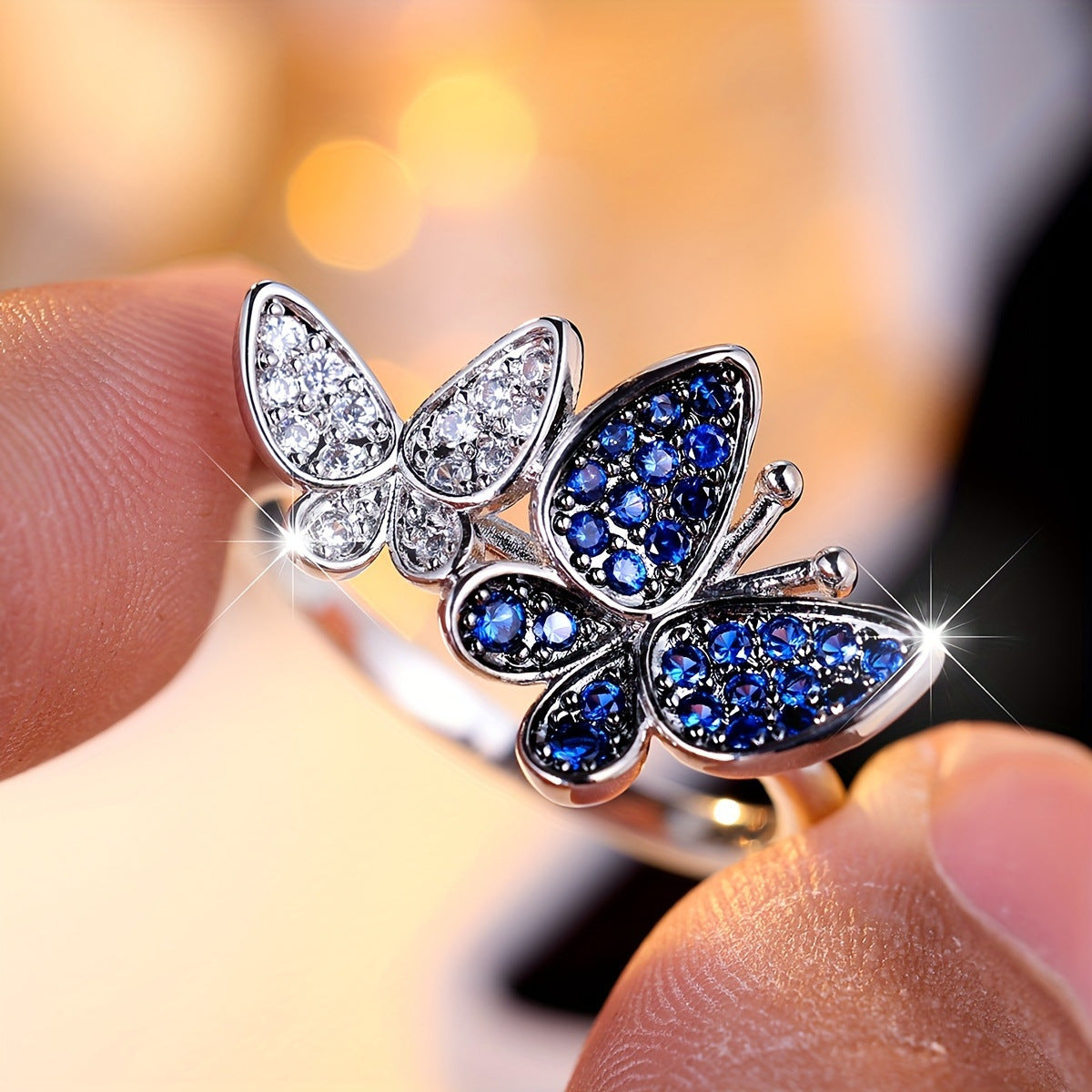 Butterfly-shaped ring with blue gemstones and clear stones on a blurred background