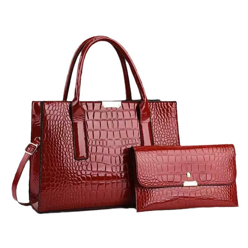 Red crocodile-patterned handbag and matching wallet on a white background