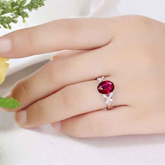 Ring with a red gemstone on a hand against a white background