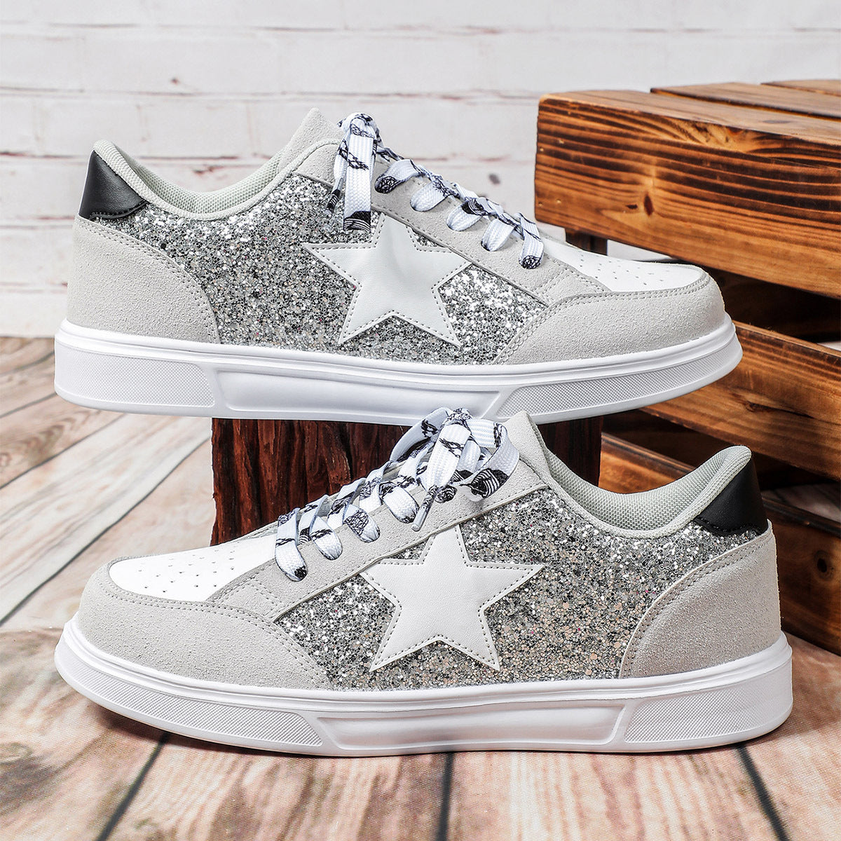 Silver glitter sneakers with white stars on a wooden surface