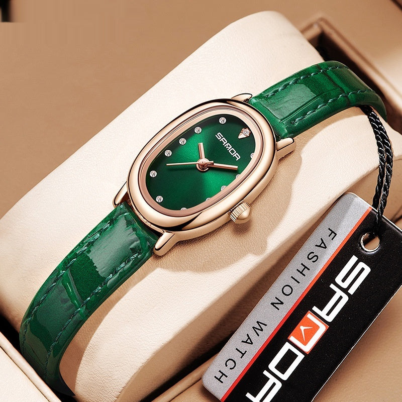 Green wristwatch with rose gold case on a beige cushion, branded 'Saward'.