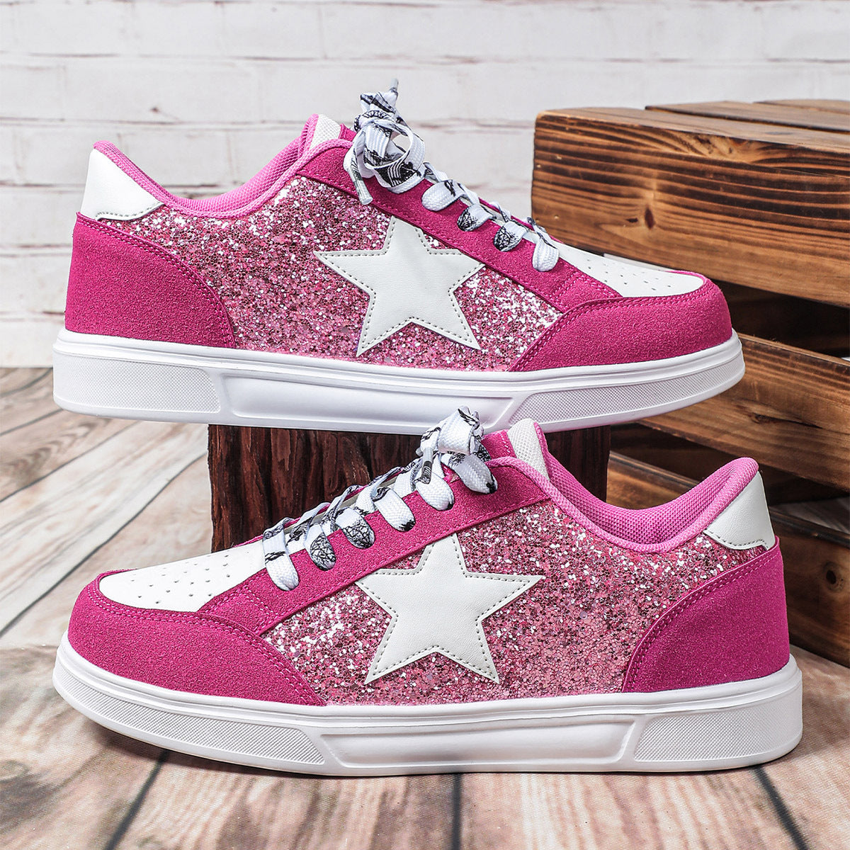 Pink glitter sneakers with white stars on a wooden surface