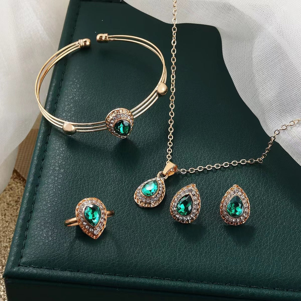 Jewelry set with gold and green gemstones on a dark green box