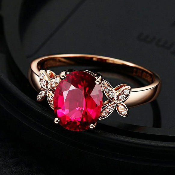 Rose gold ring with a red gemstone on a dark background