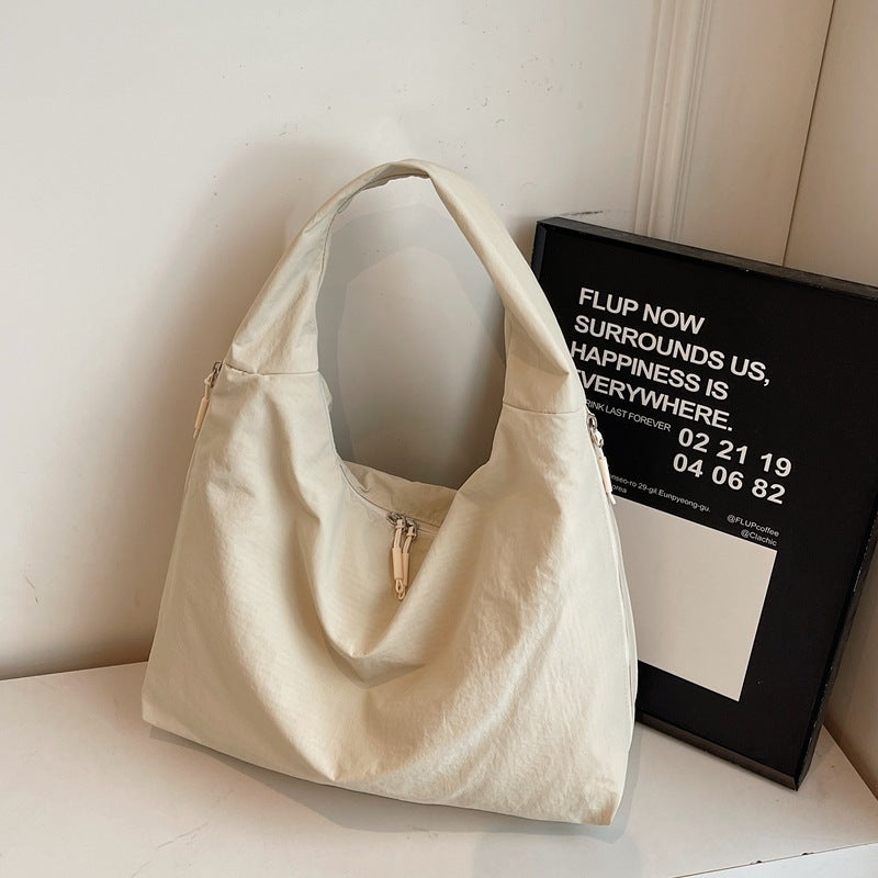Beige handbag on a white surface with a black frame in the background
