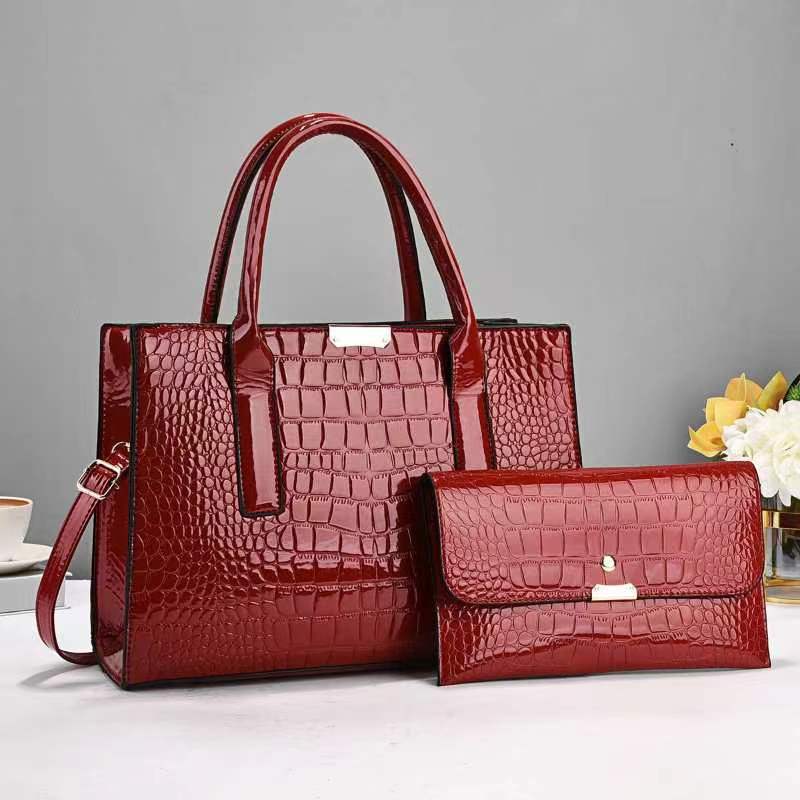 Red crocodile-patterned handbag and matching wallet on a gray background