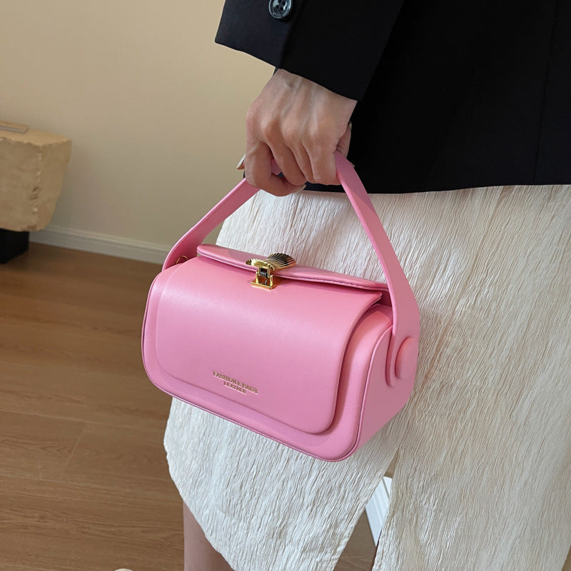 Person holding a pink handbag with a gold clasp indoors.
