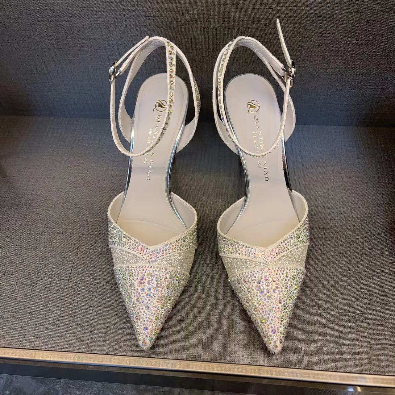 Pair of embellished high-heeled shoes on a dark surface