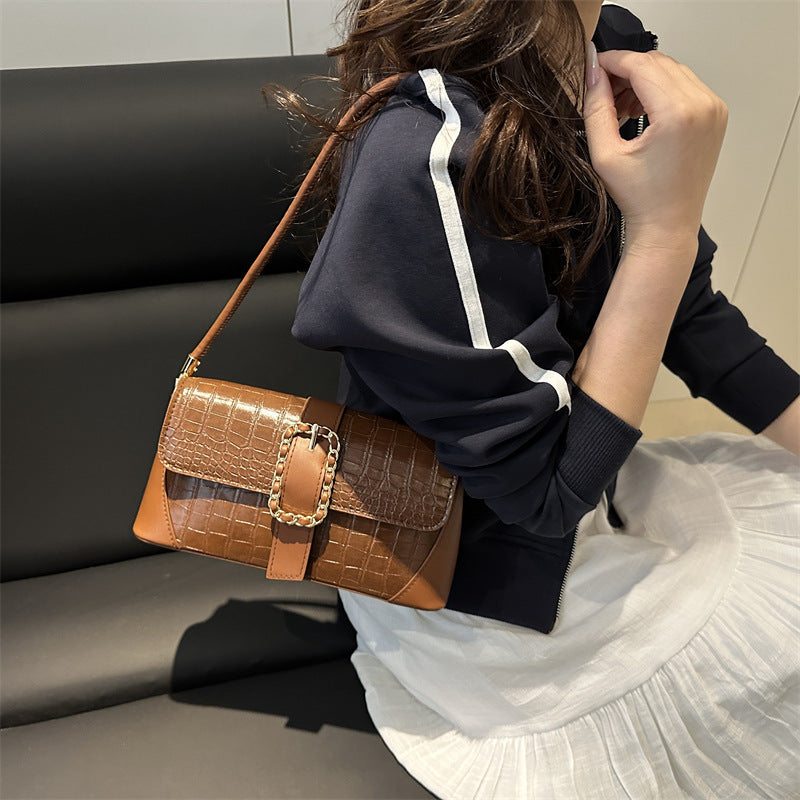 Person holding a brown handbag with a textured pattern