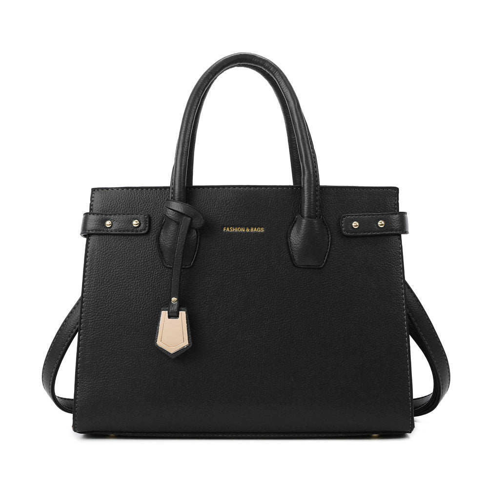 Black handbag with gold accents on a white background