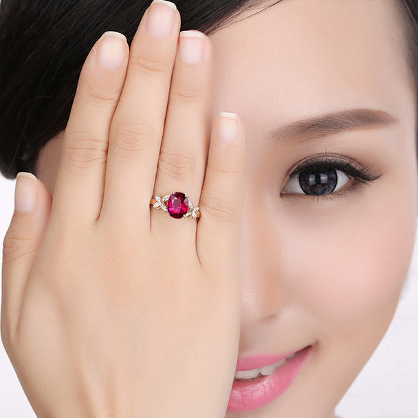 Woman wearing a ring with a red gemstone, holding her hand up to her face.