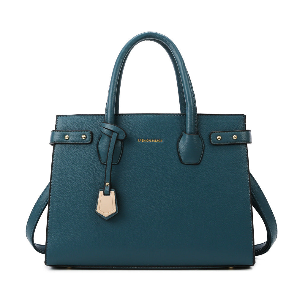 Teal handbag with gold accents on a white background