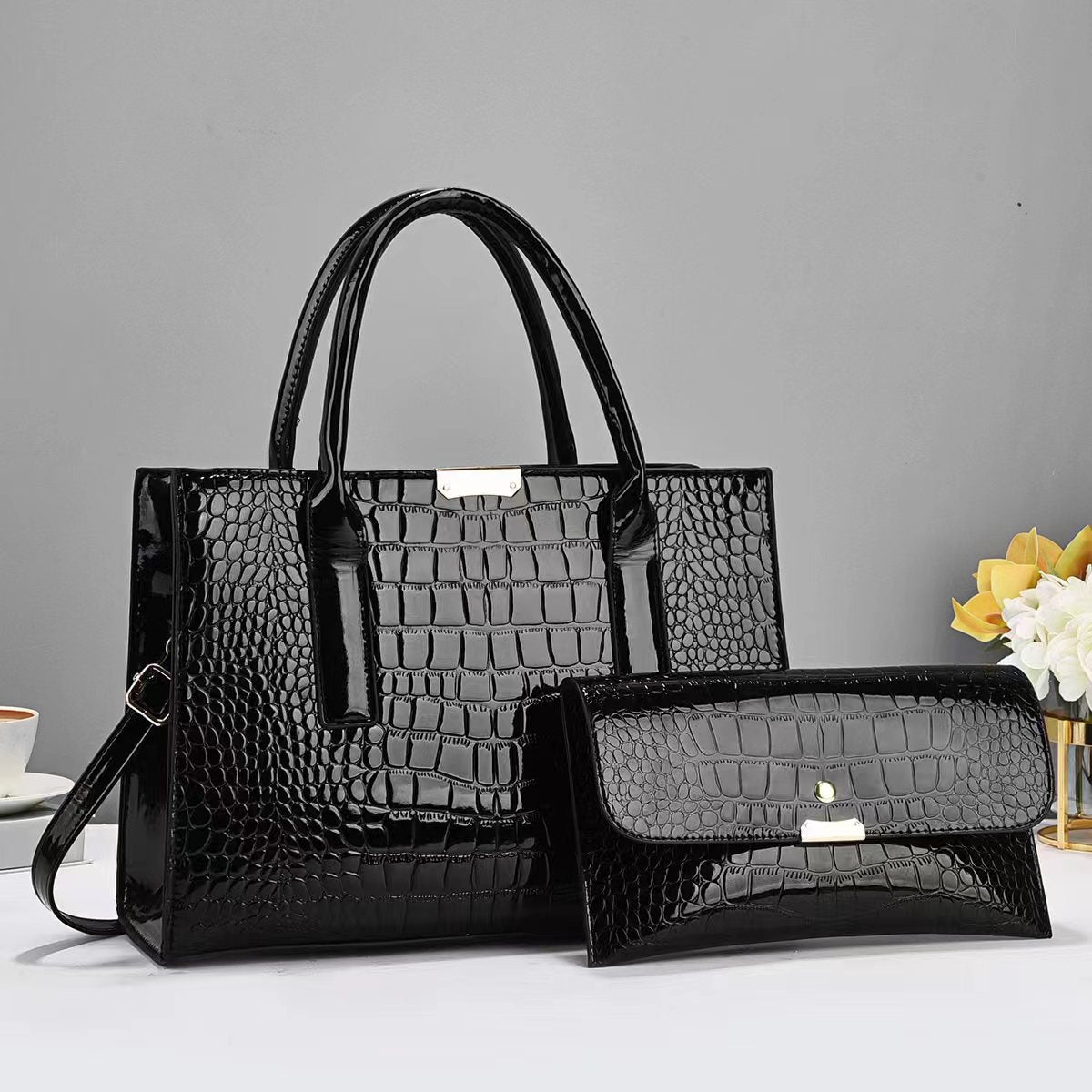 Black crocodile-patterned handbag and matching wallet on a gray background