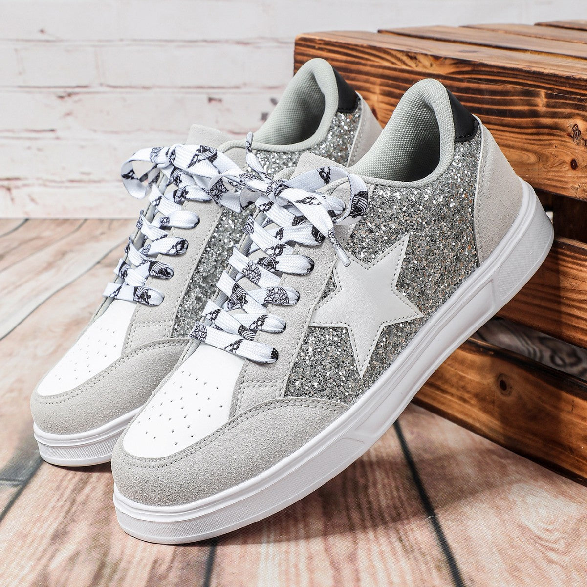 Silver glitter sneakers with white stars on a wooden surface