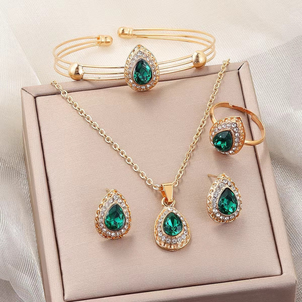 Jewelry set with gold and green gemstones on a beige box