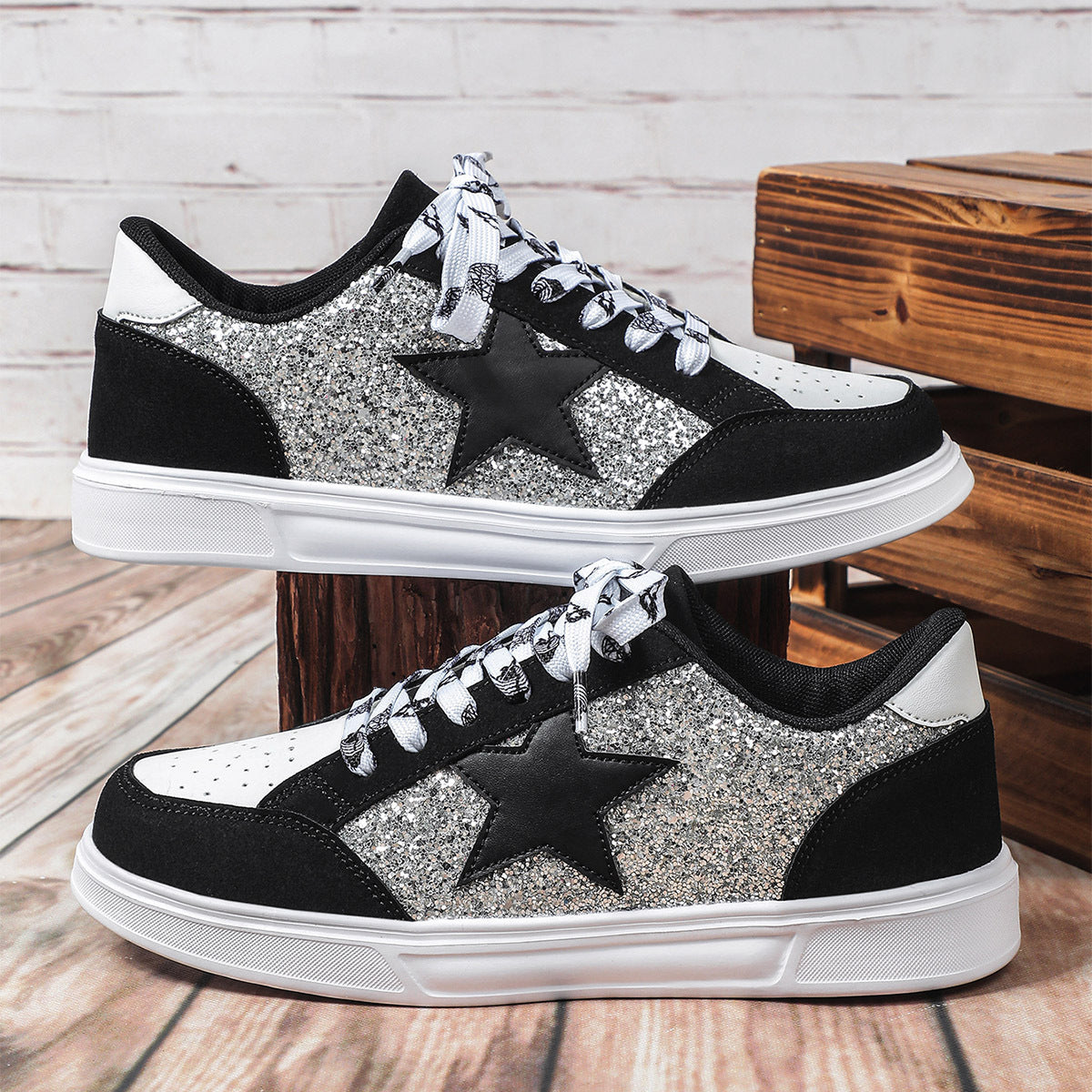 Black and silver glitter sneakers with star design on a wooden floor.